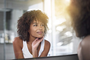 woman in mirror touching skin