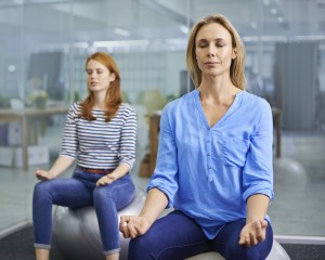 two ladies in office meditating on workout ball