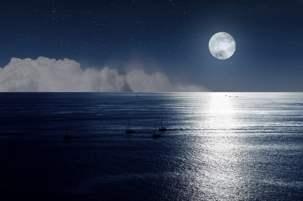 moon and clouds in the night over the ocean