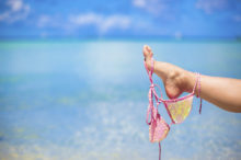 pink swimsuit on female leg on white tropical beach