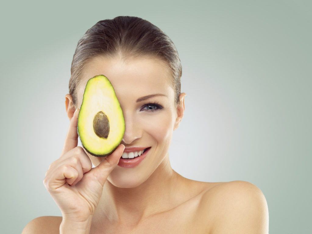 avocado being held over a woman's face