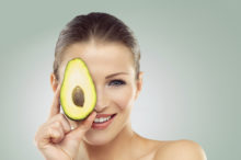 avocado being held over a woman's face