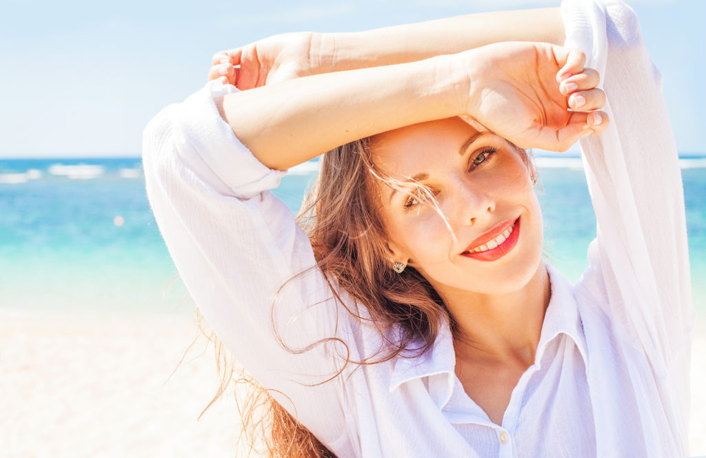 smiling woman standing in front of the ocean