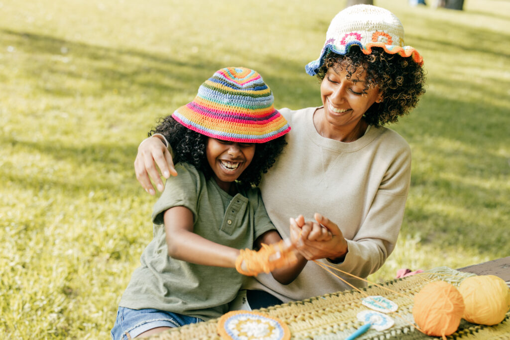 Mother and daughter laugh while playing with yarn.